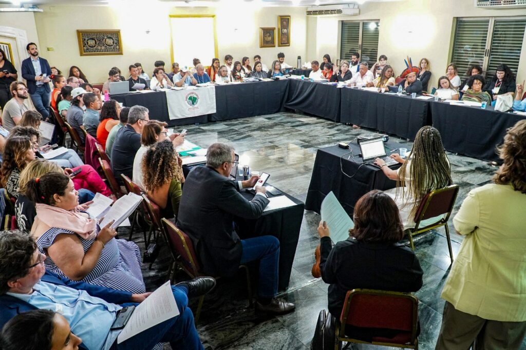 Pessoas atingidas reunidas em uma grande sala de reuniões