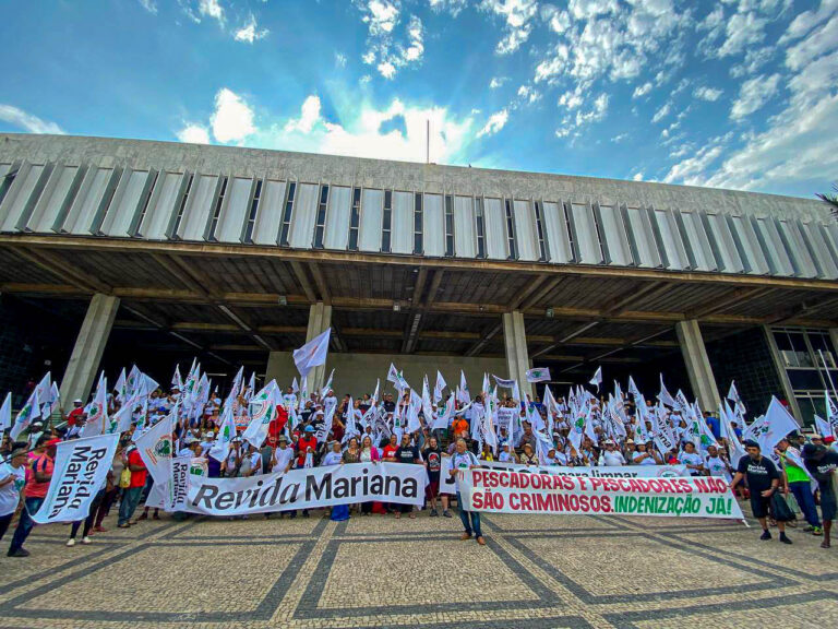 Dezenas de atingidos e atingidas posam para foto na Assembleia Legislativa de Minas Gerais, com bandeiras e faixas.